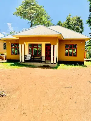 a small yellow house with a red door at Home sweet home in Uru