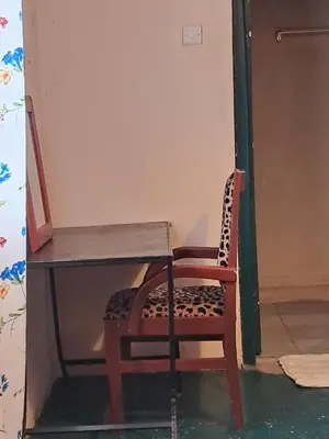 a chair sitting next to a desk in a room at Ibrahim Garden Hostel in Arusha
