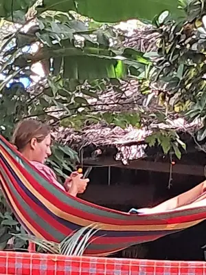 a man sitting in a hammock with a cell phone at Ibrahim Garden Hostel in Arusha