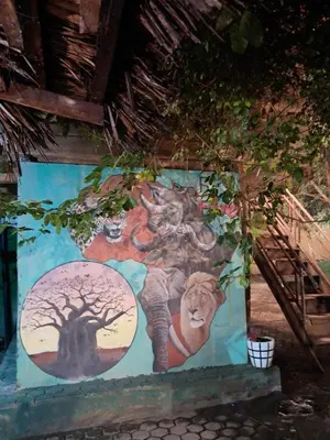a wall with a painting of a lion and a tree at Ibrahim Garden Hostel in Arusha