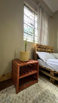 a bedroom with a bed and a table with a plant on it at Kilimanjarosons homestay in Moshi