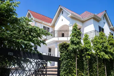 a white house with a fence and trees at Neema Stays in Arusha