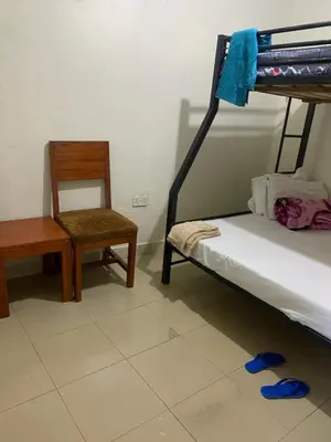 a room with a bunk bed and a chair and a pair ofippers at Amani Homestay in Arusha