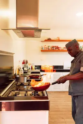 a man in a kitchen preparing food in a wok at The Scenery Residence in Arusha