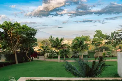a view of a lawn with trees and mountains in the background at The Scenery Residence in Arusha