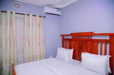 a bedroom with two white beds and a window at Hadraj Moshono Apartment1 in Arusha