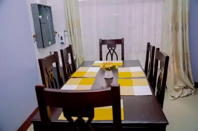 a dining room table with a yellow and white checkered table cloth at Hadraj Moshono Apartment1 in Arusha