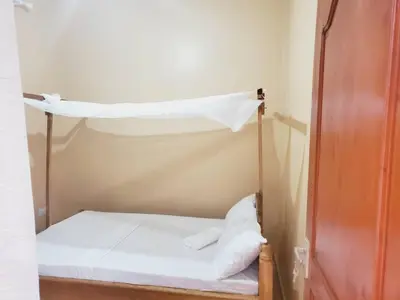 a bed in a room with a white sheet at Shilling Stay in Moshi