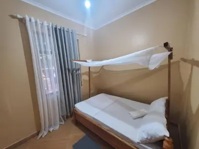 a bedroom with a bed and a window with curtains at Shilling Stay in Moshi