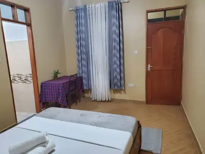 a room with a bed and a table and a door at Shilling Stay in Moshi
