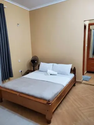 a bedroom with a large bed with white sheets at Shilling Stay in Moshi
