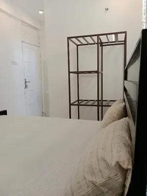 a white bedroom with a bed and a shelf at Hidalgo Home Apartment's in Moshi