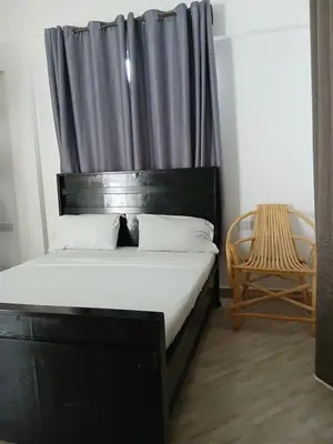 a bedroom with a bed with a black headboard and a chair at Hidalgo Home Apartment's in Moshi