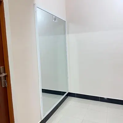 a glass shower door in a white room at Mercy Apartments Moshi in Uru