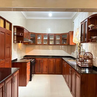 a large kitchen with wooden cabinets and black counter tops at Mercy Apartments Moshi in Uru