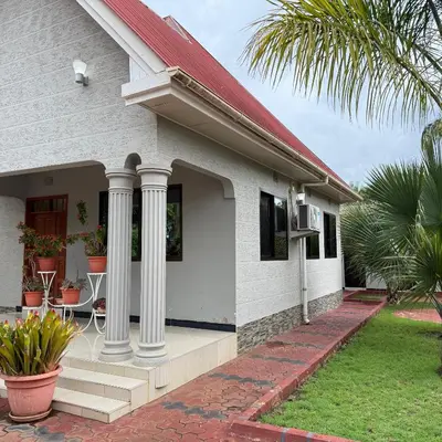 a white house with columns and a porch at Mercy Apartments Moshi in Uru