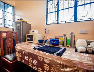 a table with a table cloth on it with a refrigerator at New Star House in Arusha