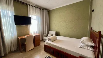 a bedroom with a bed and a desk and a television at Lush Garden Apartment in Arusha