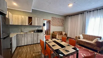 a kitchen and a living room with a table in a room at Lush Garden Apartment in Arusha