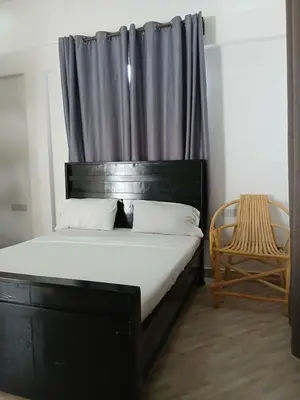 a bedroom with a bed with a black headboard and a chair at Hidalgo Explorers Home in Moshi