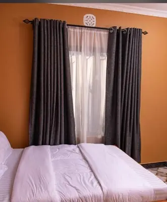 a bed in front of a window with curtains at MSF one bedroom in Arusha