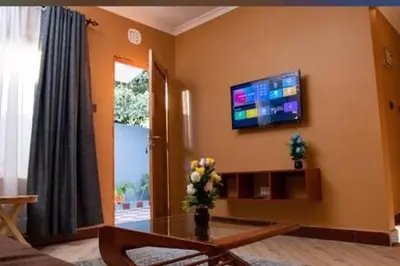 a living room with a table and a tv on the wall at MSF one bedroom in Arusha