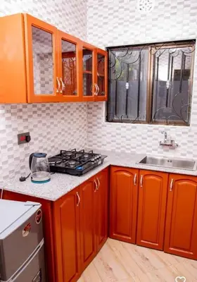 a kitchen with orange cabinets and a stove at MSF one bedroom in Arusha