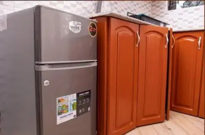 a kitchen with a stainless steel refrigerator and wooden cabinets at MSF one bedroom in Arusha