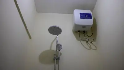 a bathroom with a toilet with a clock on the wall at Eheruro Homestay in Arusha