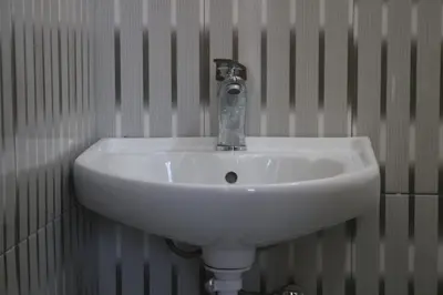 a white sink in a bathroom with a wall at Eheruro Homestay in Arusha