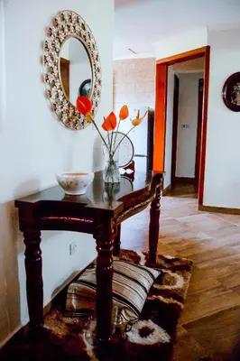 a table with a mirror and a vase with flowers on it at Rhovee Homes in Moshi