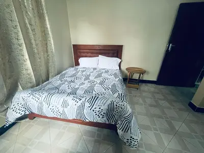 a bedroom with a bed with a black and white comforter at Abba's Homestay in Arusha
