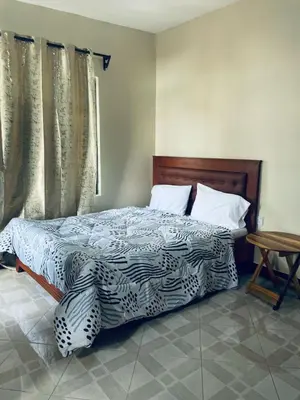 a bedroom with a bed with a blue and white comforter at Abba's Homestay in Arusha