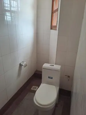 a bathroom with a white toilet with a window at Hans kili home in Moshi