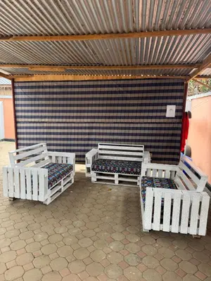 a room with three white beds in front of a wall at The Hut Hostel in Arusha