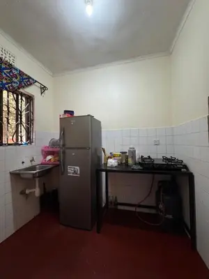 a small kitchen with a refrigerator and a sink at The Hut Hostel in Arusha