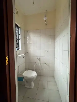 a white bathroom with a toilet and a shower at The Hut Hostel in Arusha