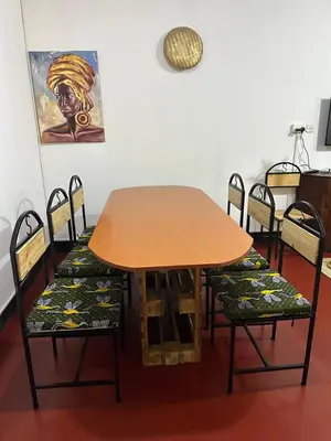 a wooden table with chairs and a table and a painting at Mardai Homestay in Arusha