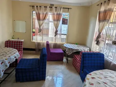 a restaurant with two tables and chairs and windows at Arusha Sunbird Lodge in Arusha