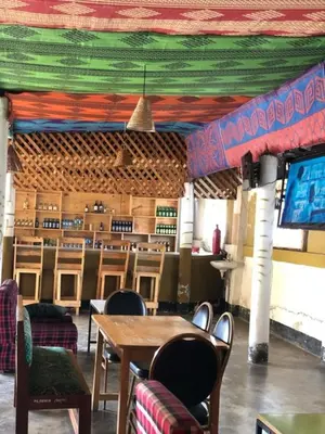 a restaurant with a table and chairs and a television at Arusha Sunbird Lodge in Arusha