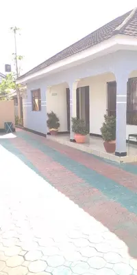 a house with a cobblestone driveway in front of it at Arusha Sunbird Lodge in Arusha