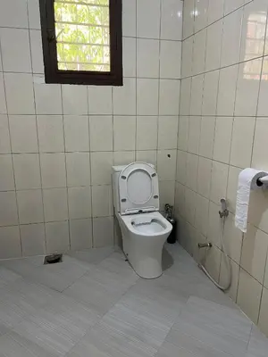 a bathroom with a toilet with the seat up at Kivuli Lodge in Moshi