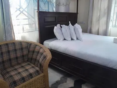 a bed with white pillows and a chair in a room at STAN LODGE Babati in Babati