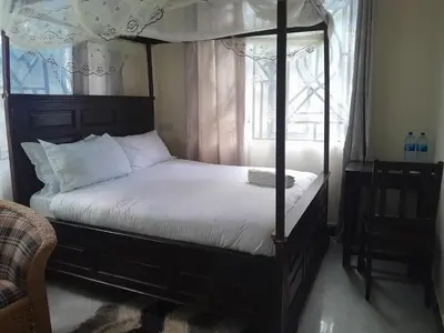 a bedroom with a four poster bed and a window at STAN LODGE Babati in Babati