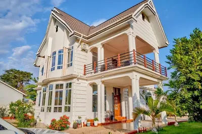 a large white house with a porch and balcony at Lake duluti serenity villas in Arusha