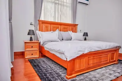 a bedroom with a large wooden bed with white pillows at Lake duluti serenity villas in Arusha