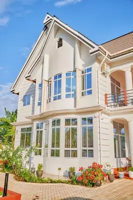 a large white house with many windows and flowers at Lake duluti serenity villas in Arusha