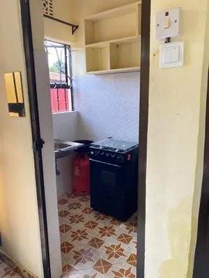 a small kitchen with a stove and a tiled floor at Comfort studio apartment in Arusha