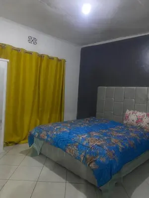 a bedroom with a bed and a yellow curtain at Mila home in Arusha