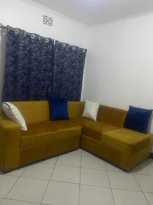 a brown couch with pillows sitting in a room at Mila home in Arusha